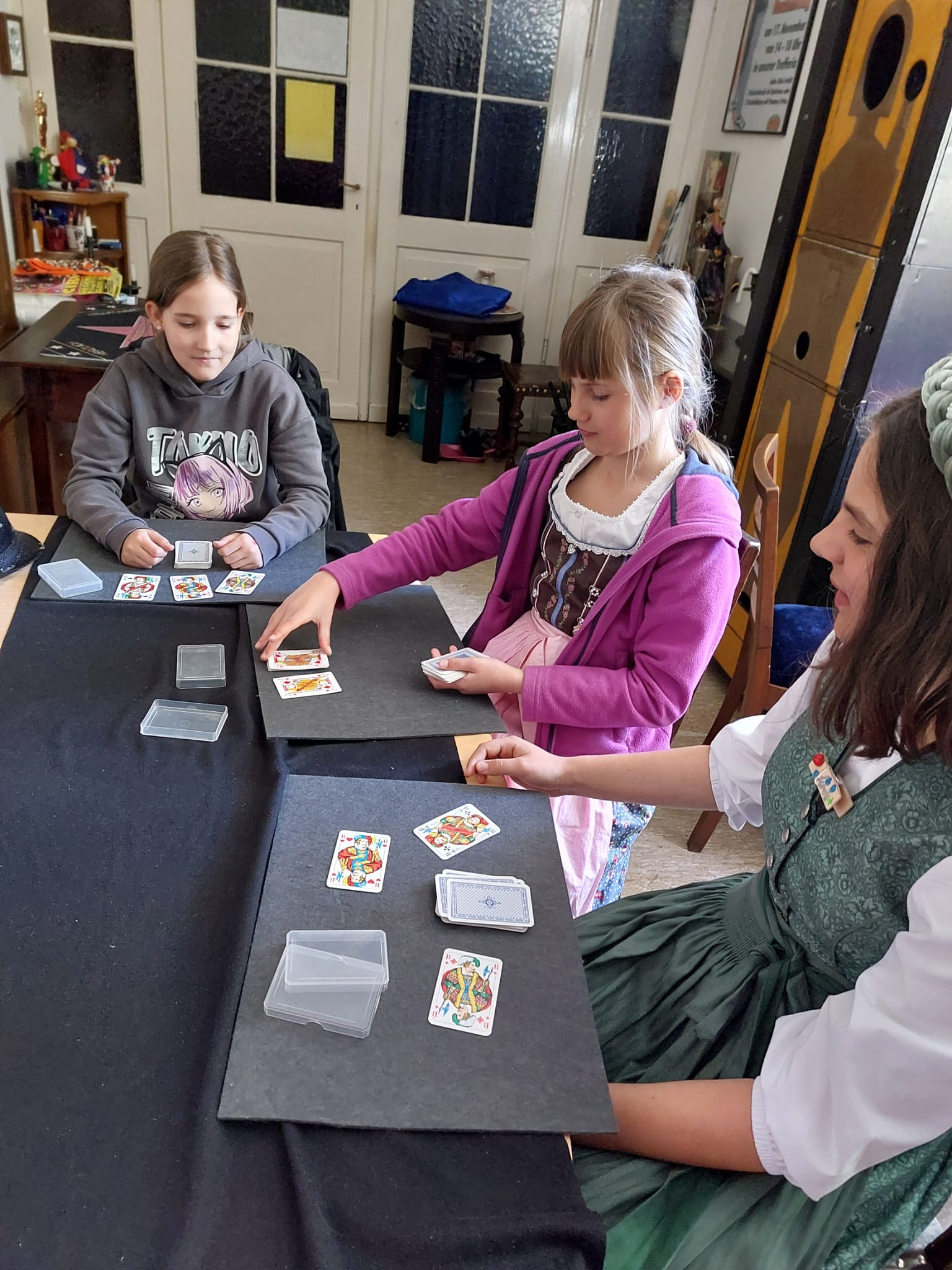 Zauberkurs: Kinder zeigen sich Kartentricks am Zaubertisch