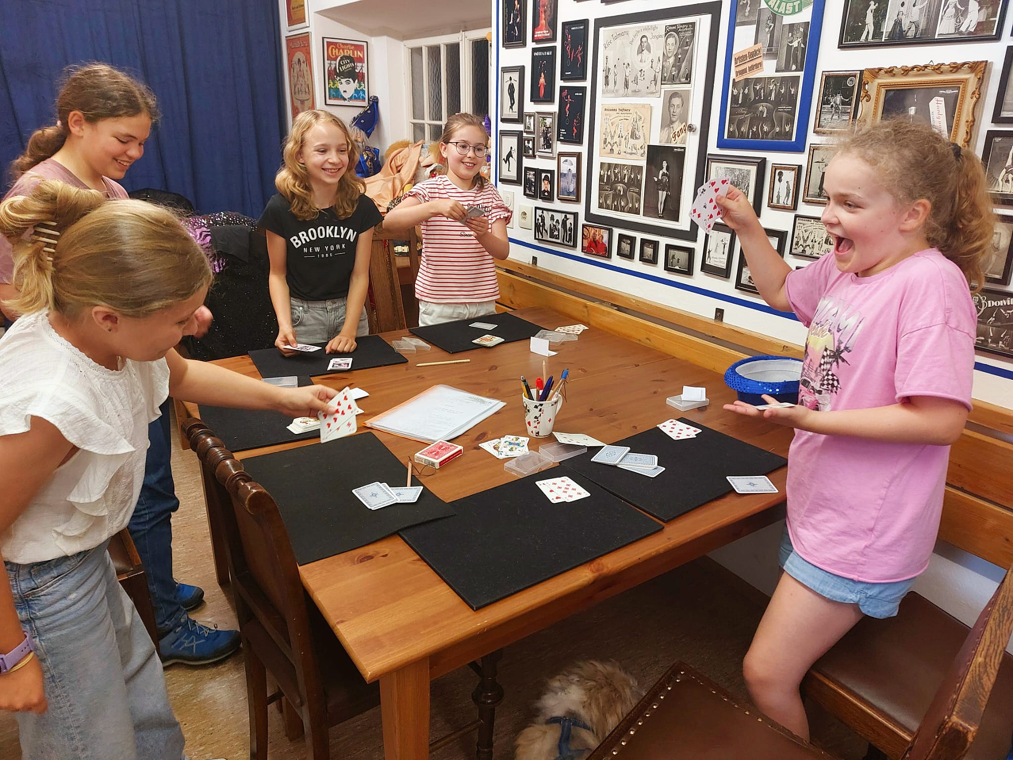 Zauberkurs: Kinder lachen und zeigen sich Kartentricks am Tisch