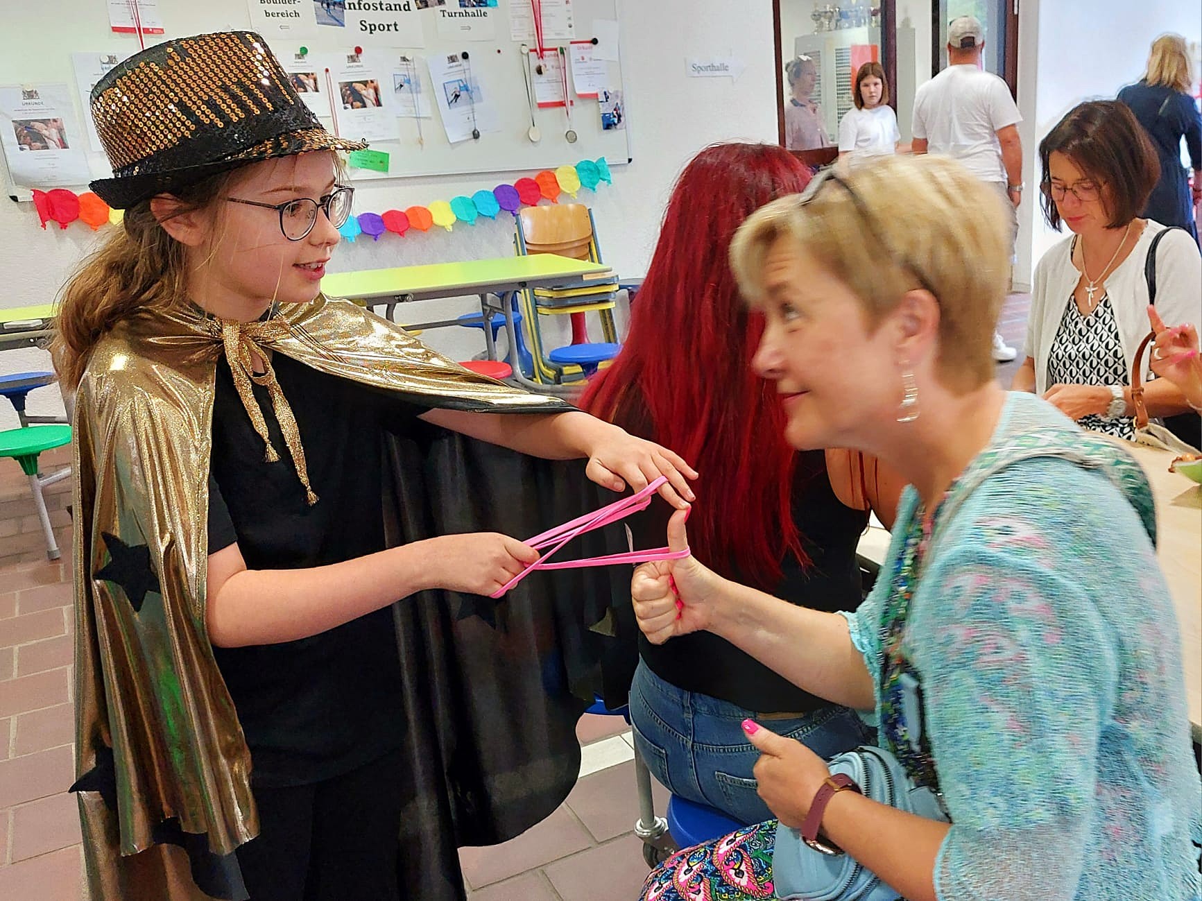 Zauberkurs: Kind im goldenen Umhang zeigt einen Gummiband-Trick