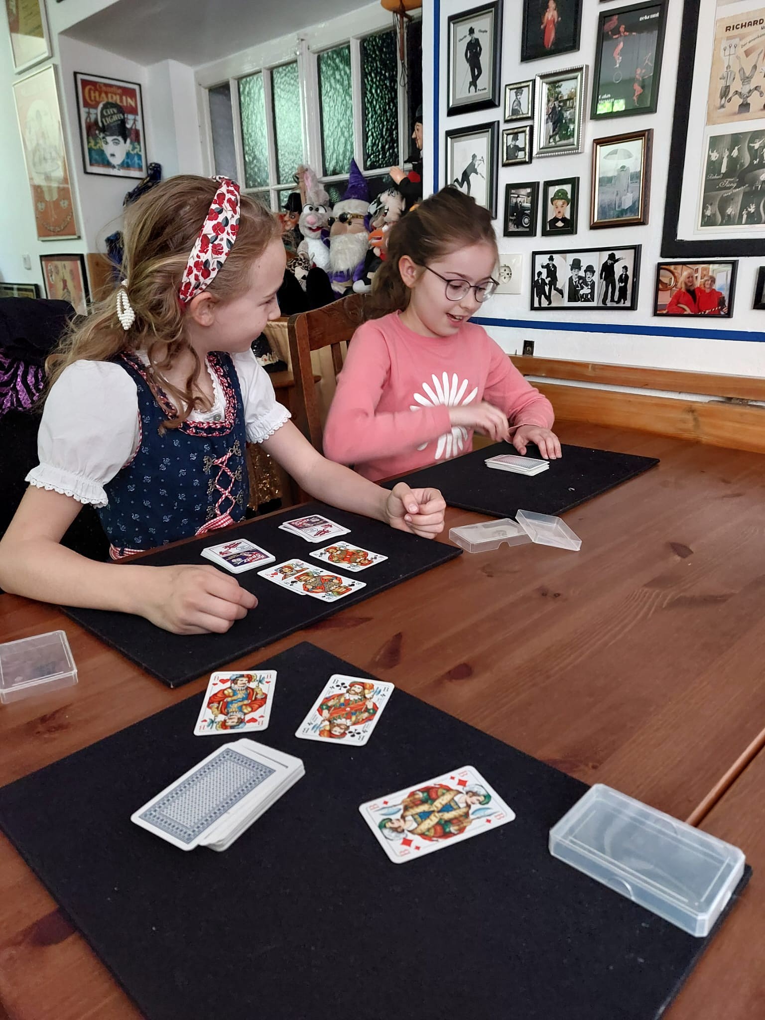 Zauberkurs: zwei Mädchen üben Kartentricks am Tisch
